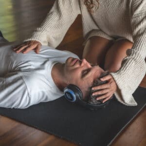 A man and woman laying on the ground with headphones.