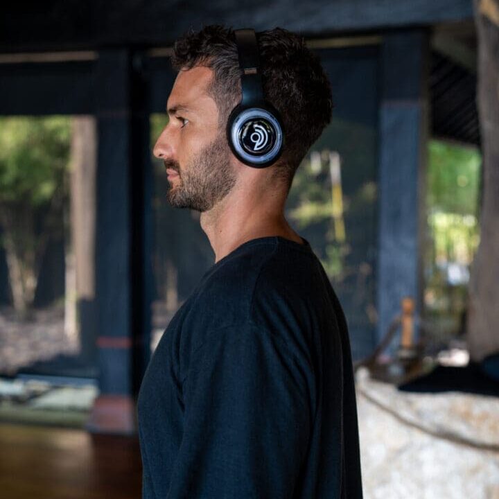 A man wearing headphones while standing in front of a fire place.